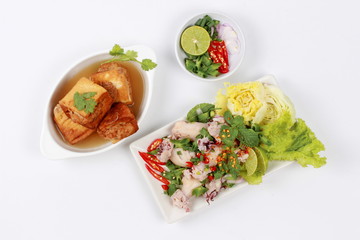 Gold bar soup as fried tofu wrap minced pork in soup served with spicy and sour mixed herb salad with squid wrap minced pork . Top view.