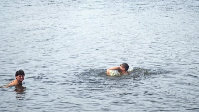 Teenager next to the mother swims in the lake. Slow motion . High speed camera