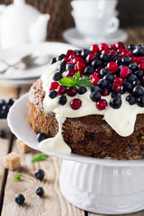Cake with fresh berries and cream on old wooden background. Selective focus.