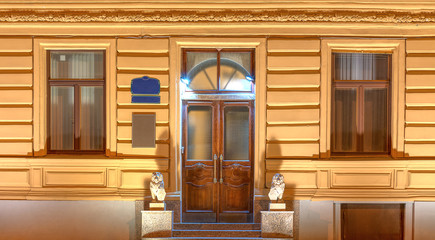 Two windows and door in a row on night illuminated facade of urban office building front view, St. Petersburg, Russia.