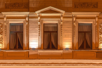 Three windows in a row on night illuminated facade of urban office building front view, St. Petersburg, Russia.