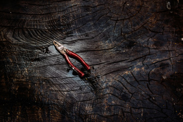 Naklejka premium Old and rusty pliers on a dark wooden background.