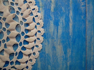 красивая старая вязаная салфетка лежит на синих деревянных досках   
