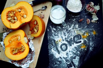 Fresh pumpkin slice on a black wooden table with flour texture. Autumn cooking background. Healthy eating. Top view.