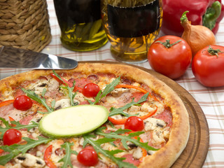 italian pizza on a wooden board with oil bottles, tomatoes, pepper and onion on background