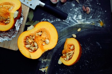 Fresh pumpkin slice on a black wooden table with flour texture. Autumn cooking background. Healthy eating. Top view.