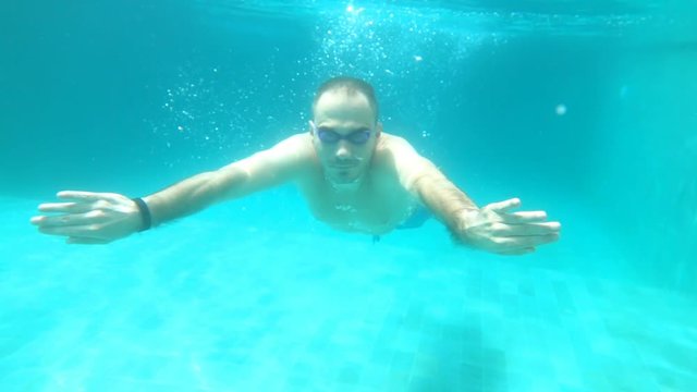 Young man swimming under water, super slow motion
