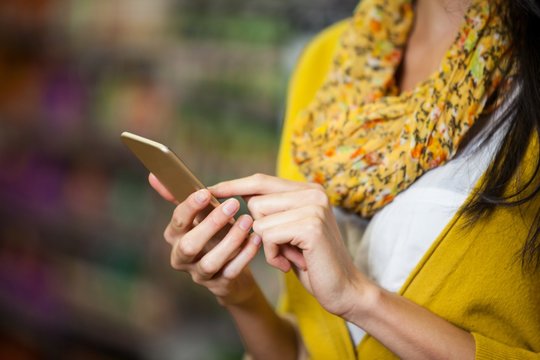 Woman Using Mobile Phone In Grocery Section