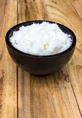 Place rice in a cup on a wooden table.