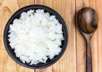 Place rice in a cup on a wooden table.