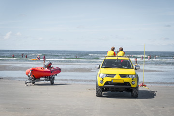 Zwei Rettungsschwimmer sitzen auf einem Geländewagen und beobachten Badegäste 