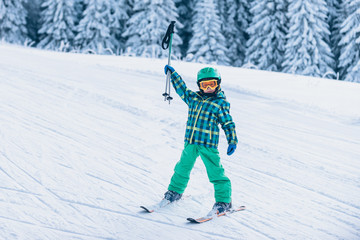 Fototapeta na wymiar Little skier cheering, holding ski poles up