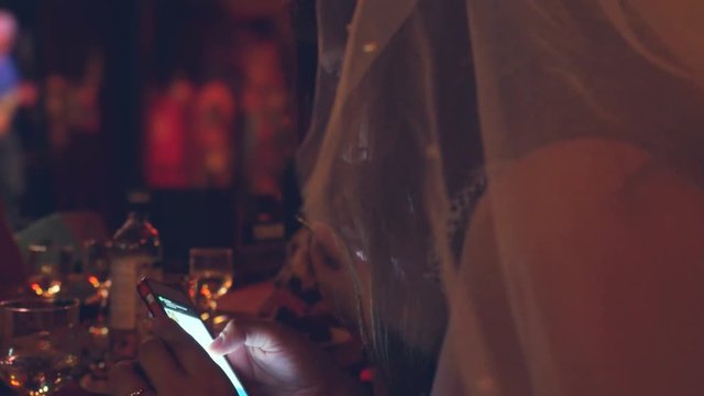 Young bride using phone at the table. 3840x2160