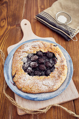 Handmade cherry pie on a blu dish, on a wooden table. Country style.