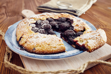 Handmade cherry pie on a blu dish, on a wooden table. Country style.