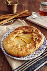 handmade apple pie on a dish over a napkin in a country style, cinnamon and hony in the background