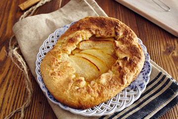handmade apple pie on a dish over a napkin in a country style, cinnamon and hony in the background