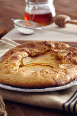 handmade apple pie on a dish over a napkin in a country style, cinnamon and hony in the background