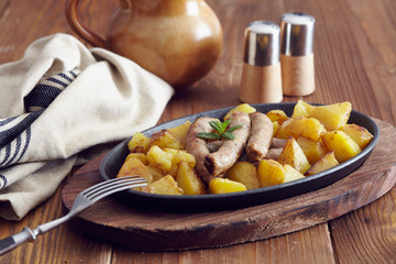roasted sausages and potatoes on a wooden table
