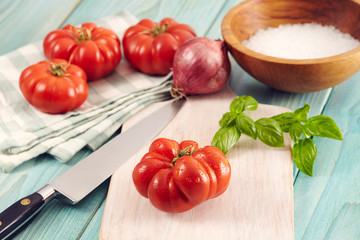 Tomatoes corleone type for sauce on a aquamarine wooden table with basil and onion