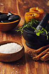 Spa tools, bath salt, mortar with herbs, a bowl with hot stones and candles, some cinnamon sticks...