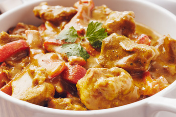 Curry chopped pork in a bowl with basmati rice on a bamboo placemat on a blue wooden table