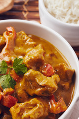 Curry chopped pork in a bowl with basmati rice on a bamboo placemat on a blue wooden table