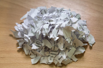 A pile of torn paper with text on wooden table