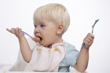 Cute young boy eating with messy face