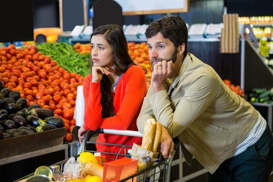Bored couple with shopping trolley in organic section - Powered by Adobe