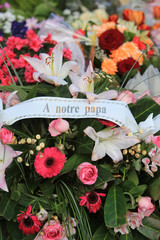 "A mon papa." Gerbe de fleurs sur une pierre tombale.