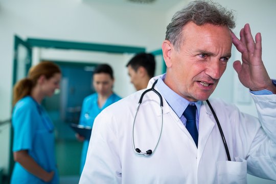 Tensed doctor standing in corridor