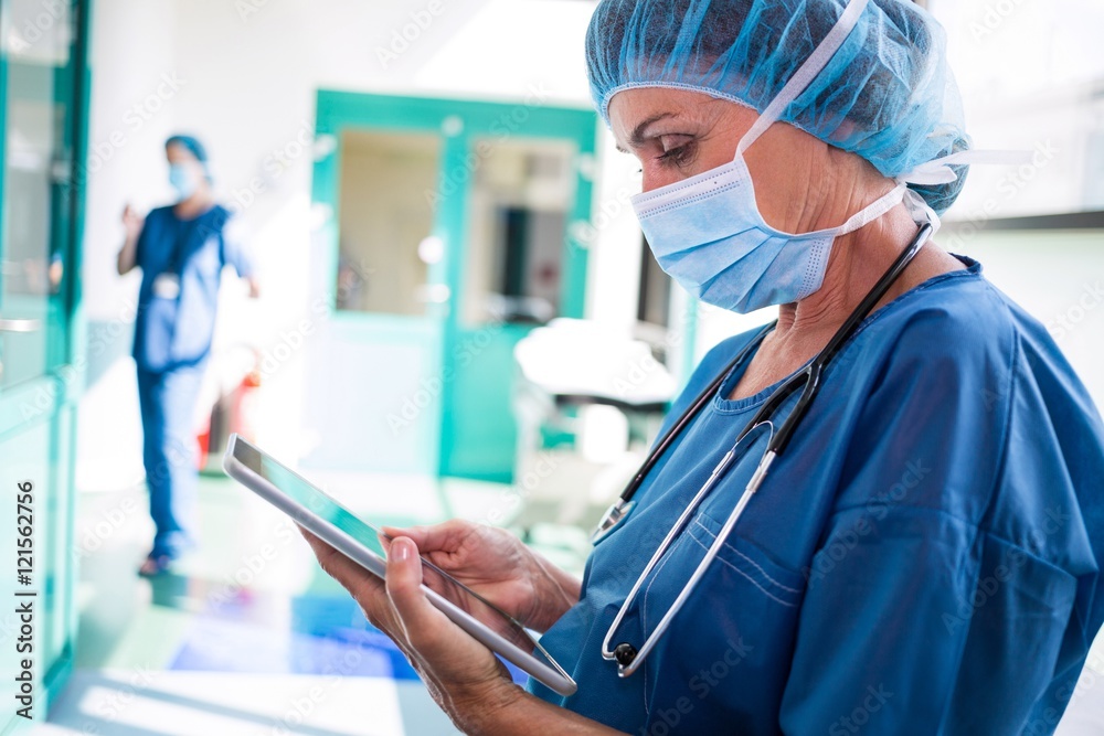 Poster surgeon using digital tablet in corridor