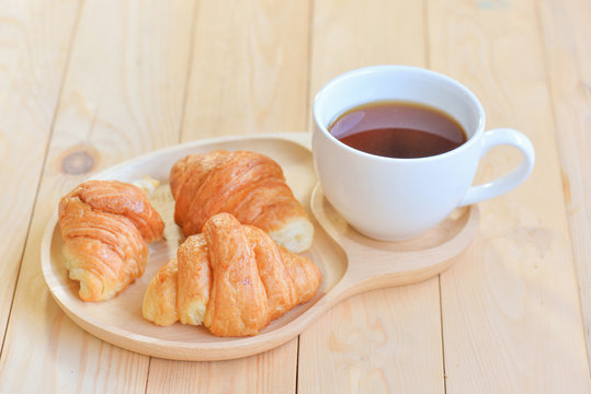 croissants with cup of coffee on wooden background