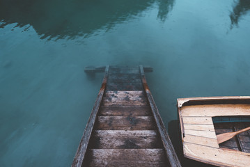 wood stair in Braies lake with a wood boat and blue water - 121562909