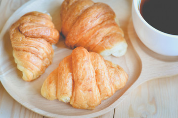 croissants with cup of coffee on wooden background