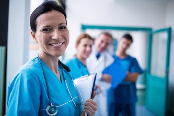 Portrait of smiling surgeon holding a clipboard in corridor