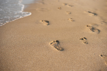 Children footprints in the sand. Human footprints leading away from the viewer. A row of footprints in the sand on a beach in the summertime. Summer Vacation