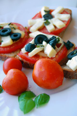 Bruschetta with tomatoes, black olives, goat cheese, herbs and oil on toasted bread