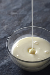 Pouring condensed milk in the glass bowl vertical