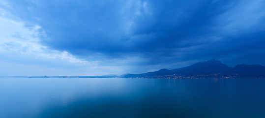 Obraz premium Lago di Garda in the evening (Garda Lake), with the lights of the coast of Lombardy, Italy