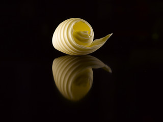 Butter slice on a black background. Reflection.