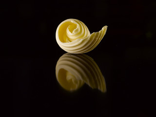 Butter slice on a black background. Reflection. - obrazy, fototapety, plakaty