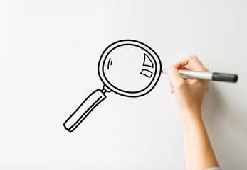 close up of hand writing magnifier on white board