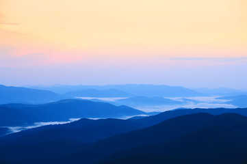 silhouettes of mountain peaks in the fog down in the evening. Roerich minimalism
