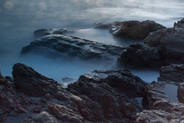 Ocean waves crashing onto the rocks in the sunset