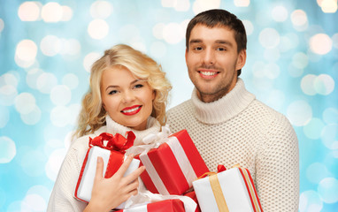 happy couple in sweaters holding christmas gifts