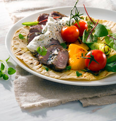 Tortilla, meat slices, tomato, grilled pepper etc. Light background. Sun lights in studio. 
