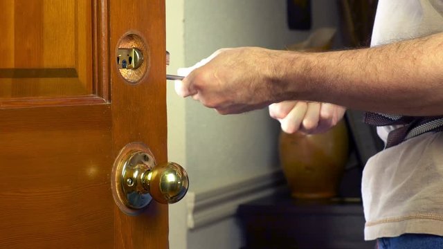 Handyman replacing a door lock in a home