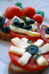 Bruschetta with tomatoes, black olives, goat cheese, herbs and oil on toasted bread